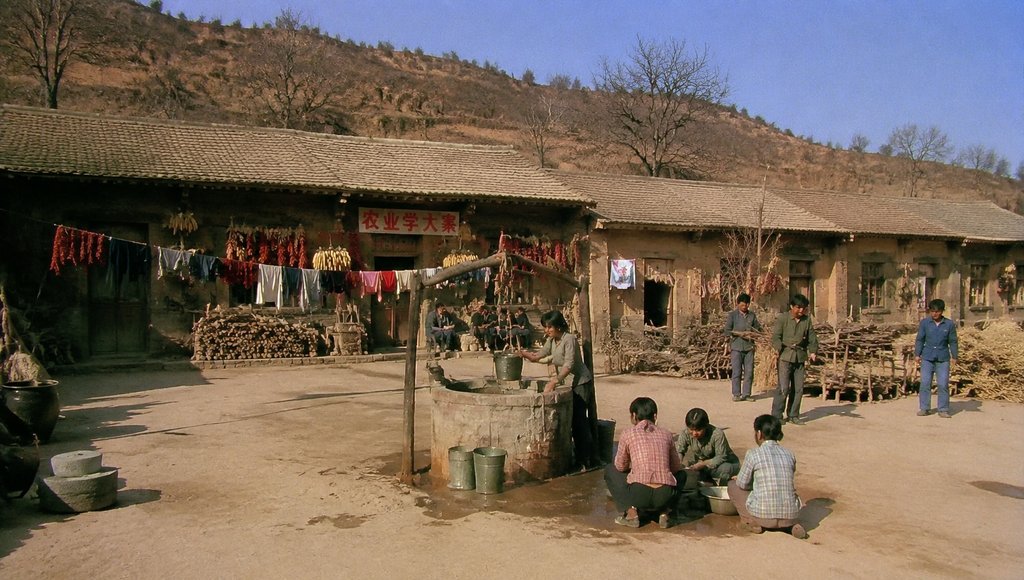 知青大院土坯房前,人们在公用井边洗衣,晾晒衣物与辣椒,年代怀旧写实场景