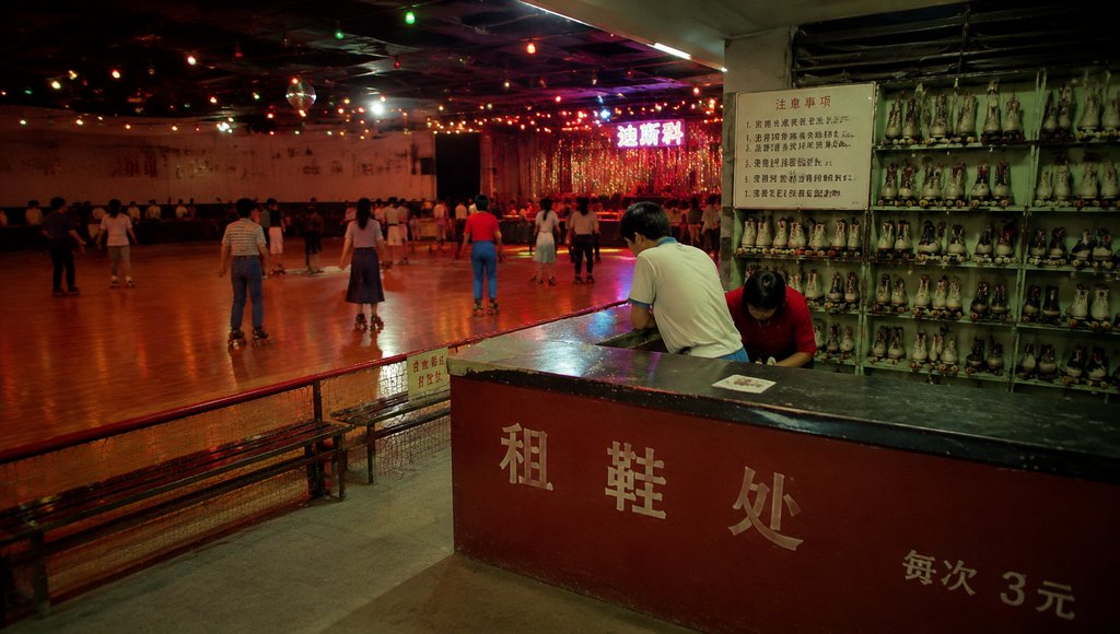 怀旧年代溜冰场，木地板上人们滑旱冰，租鞋台前陈列轮滑鞋，彩灯闪烁，复古写实风格