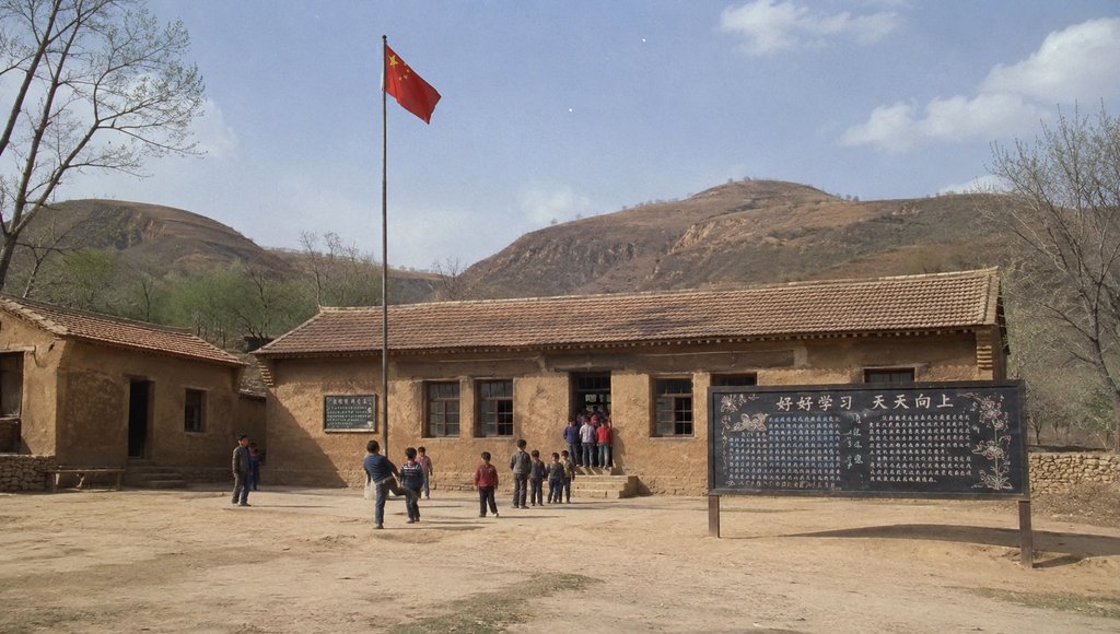 乡村小学土坯教室前,孩子们在旗杆下活动,黑板报写着‘好好学习 天天向上’,背景是黄土高原山丘,怀旧写实风格