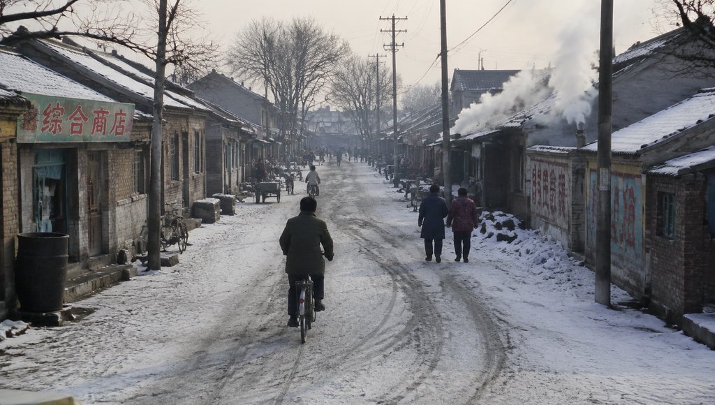 雪后冬日老街，行人骑车穿行，屋檐积雪，烟雾缭绕，怀旧写实风格