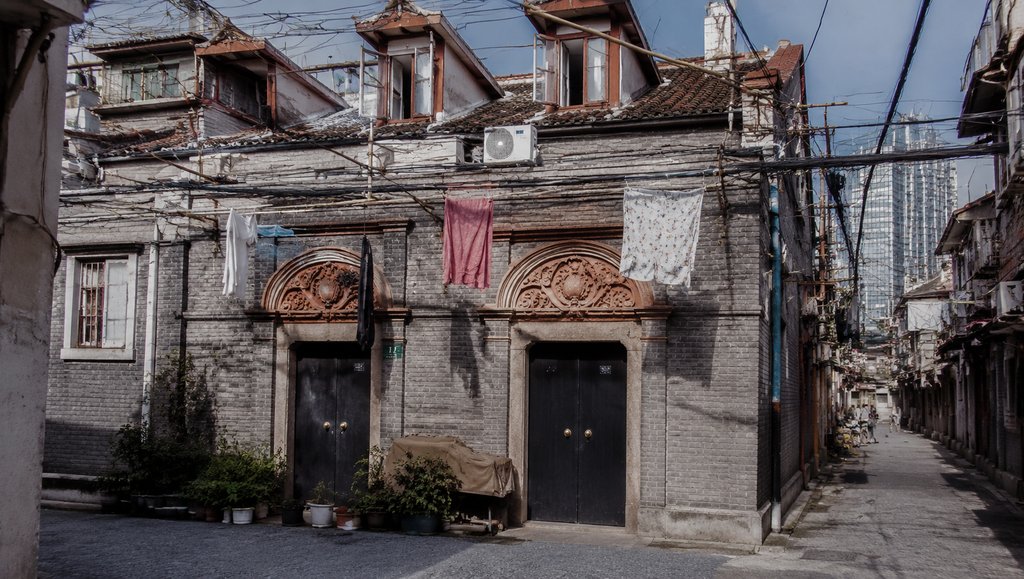 石库门里弄老建筑,清水砖墙配黑漆门,老虎窗与悬挂衣物,年代怀旧写实风格