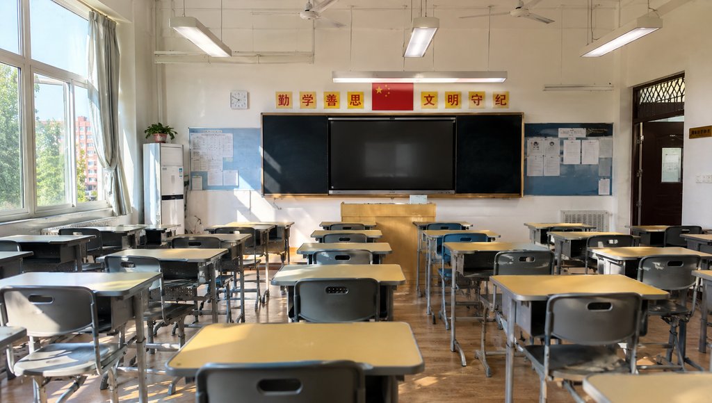 明亮的学校教室，成排课桌椅，黑板讲台，中国国旗和标语，现代都市写实风格