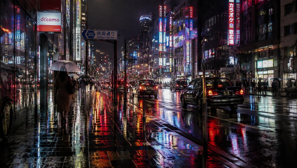 雨夜城市街道，霓虹灯倒映在湿漉漉的地面，行人撑伞行走，车灯闪烁，现代都市夜景写实画面