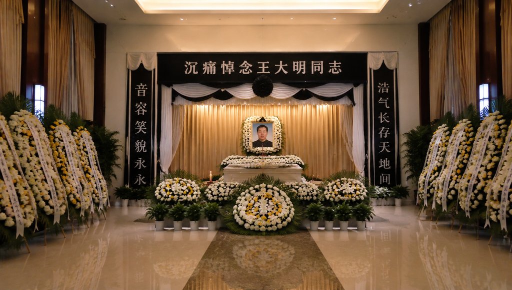 殡仪馆告别厅内景,遗像前摆放花圈与白幛,庄严肃穆的现代都市写实场景