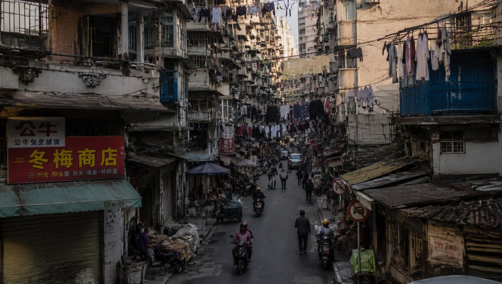 城中村街巷,握手楼林立,空中挂满晾衣,电线交错,现代都市写实场景
