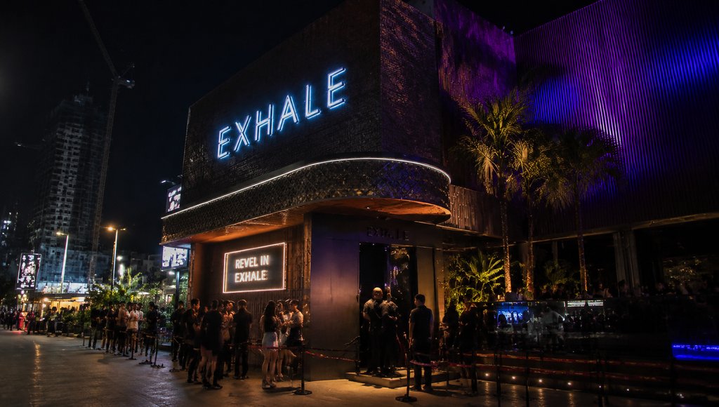 夜晚霓虹灯照亮的夜店Exhale外观，人群排队入场，现代都市建筑风格