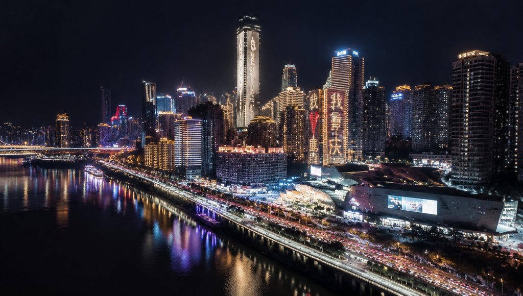 夜幕下灯火辉煌的现代都市天际线,江岸车流不息,高楼林立,灯光倒映水中,写实风格