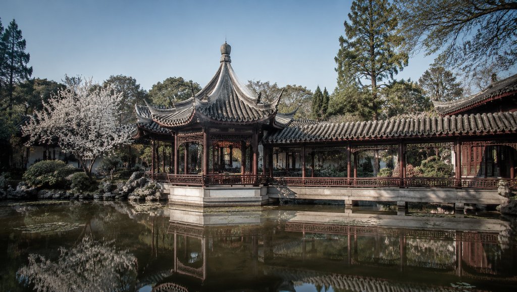 古典中式亭台水榭,飞檐攒尖屋顶,雕栏游廊倒映水中,春日樱花盛开,写实风格建筑