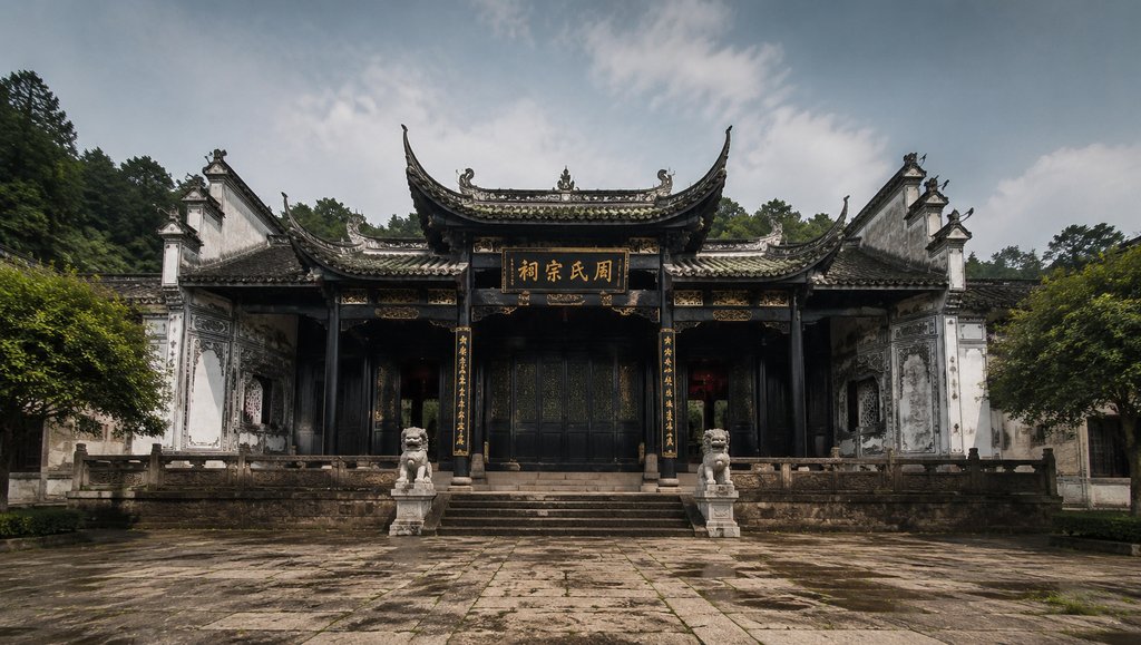 中国传统宗祠建筑，飞檐马头墙，黑漆大门，石狮守卫，悬匾题字，写实风格