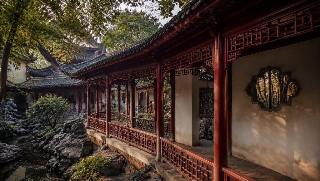中式古典园林回廊,红柱卷棚顶,漏窗设计,绿树环绕,写实建筑风格
