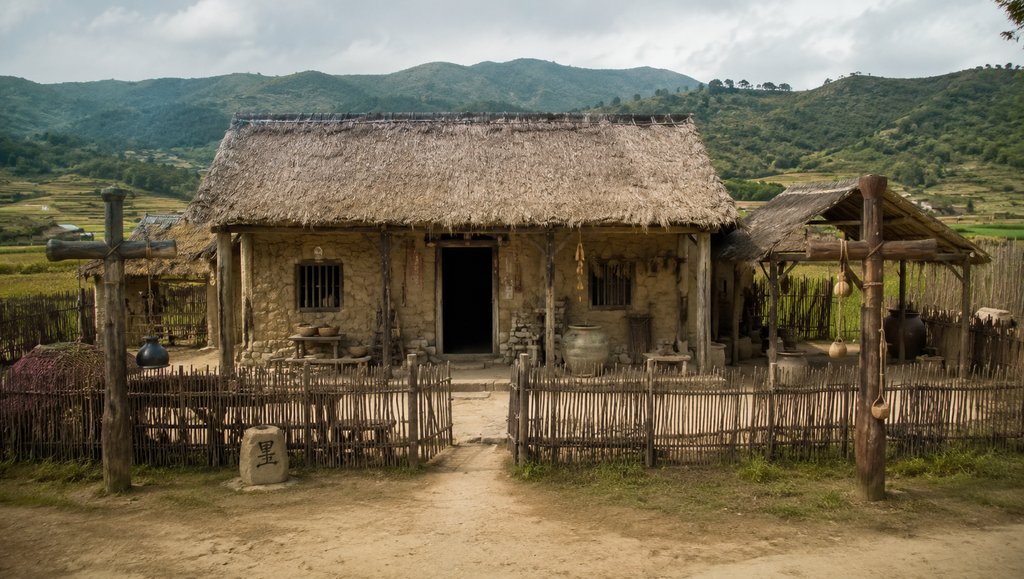 商周风格陶屋村舍，夯土墙体，茅草屋顶，篱笆院落，写实古风建筑